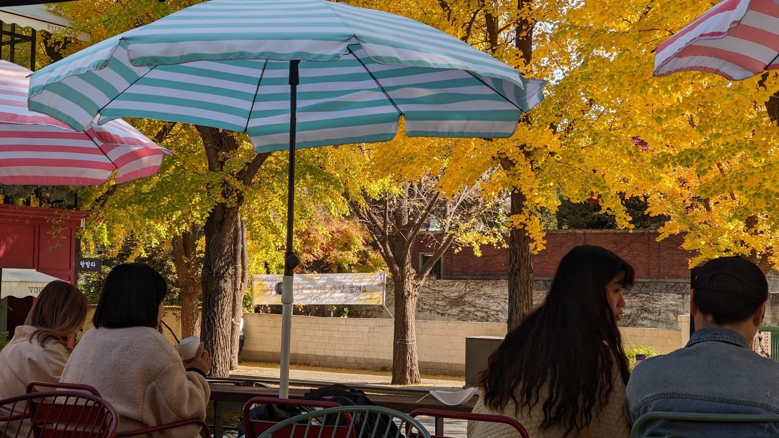 People sitting under striped umbrellas on a neighbourhood terrace