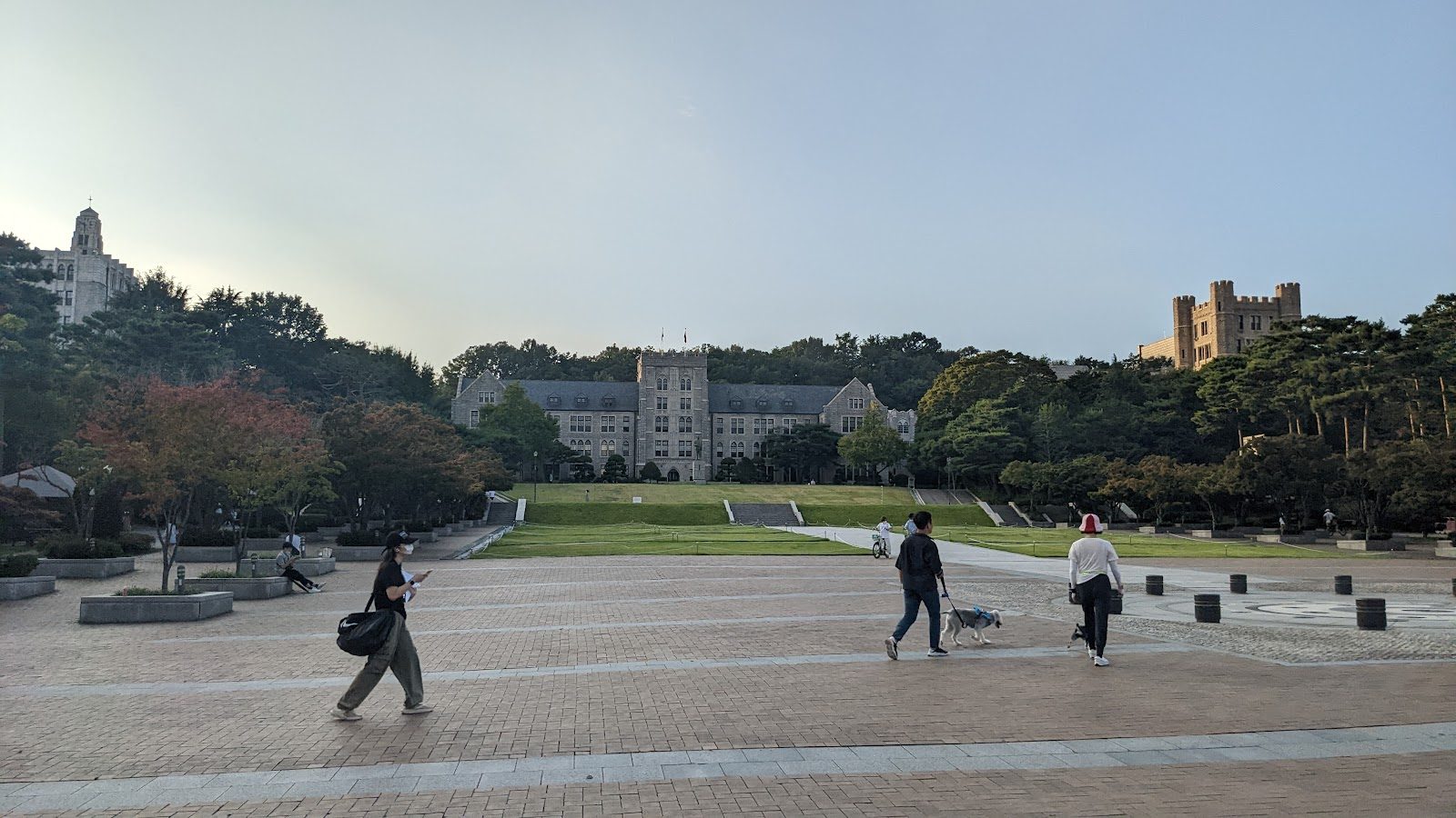 People crossing a university plaza in Seoul at dusk