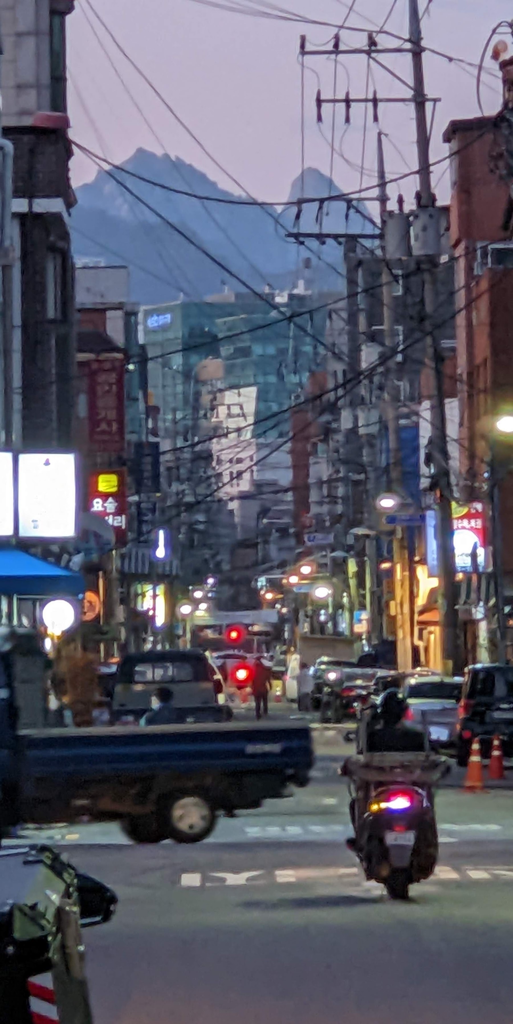A narrow Seoul street lined with shop signs at dusk